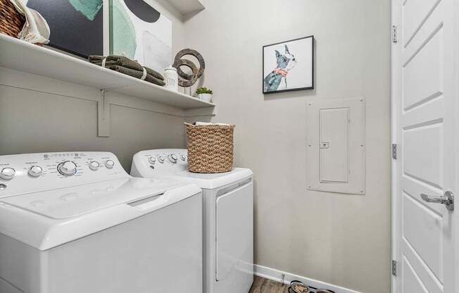 A laundry room with a washer and dryer and a basket on top of the dryer.