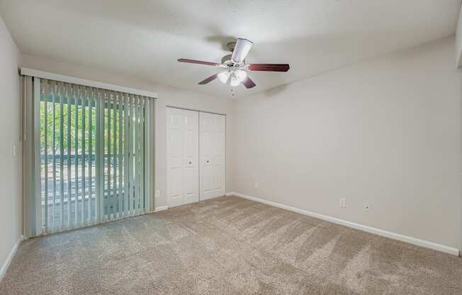 A room with a ceiling fan and carpeted floor.