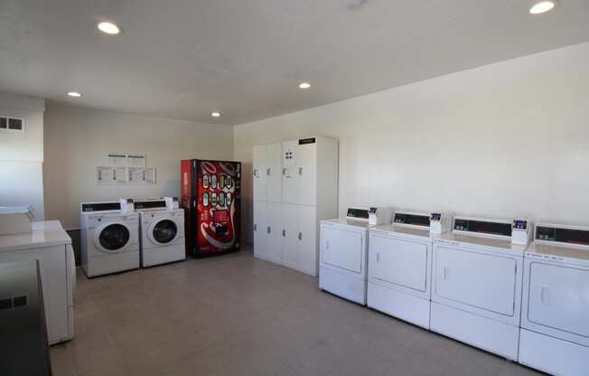 a laundry room with white washers and dryers and a red vending machine