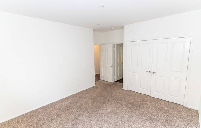 a bedroom with white walls and carpet and a closet at The Vines at Riverpark, LLC, California, 93036