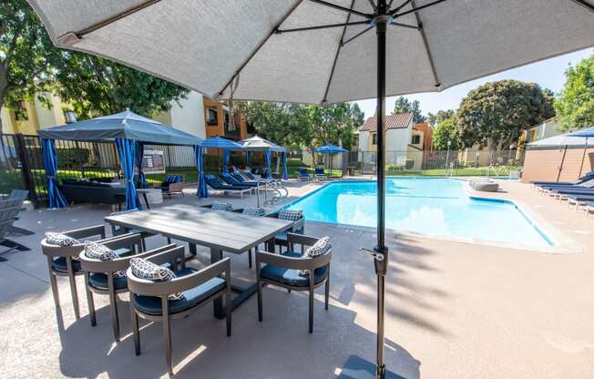 Pool view with dining furniture, cabanas, and sparkling pool
