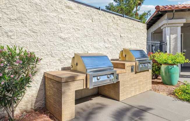 A small outdoor grill area with a stone wall and a green pot.