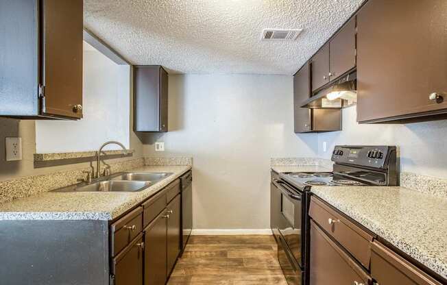 A kitchen with brown cabinets and a granite countertop.