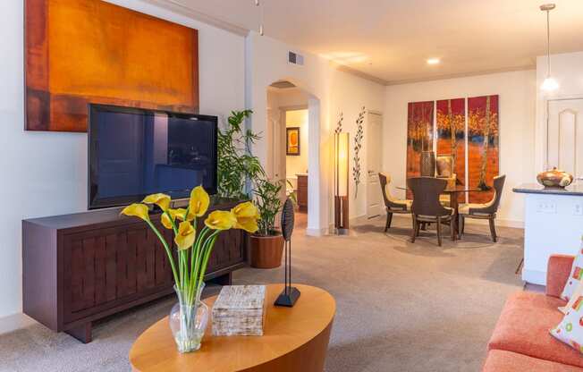 a living room with a tv and a dining room in the background