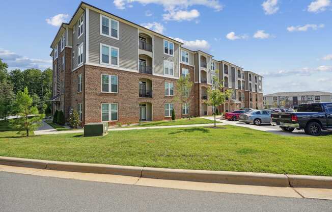 an apartment building with a lawn and a parking lot