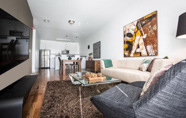 Model unit living room with brown rug, glass coffee table and white & gray couches