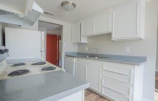 a kitchen with white cabinets and a stove and a sink at Parkside Gardens Apartments, Sparks Nevada
