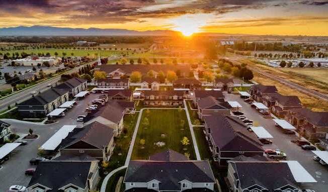 A sunset view of a residential neighborhood with houses and parked cars.