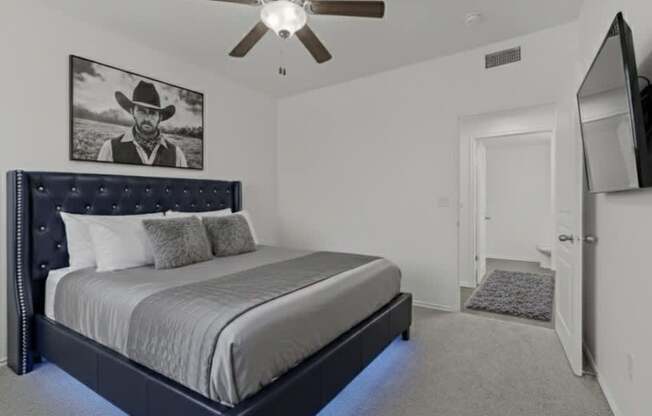 A bedroom with a large bed and a ceiling fan.