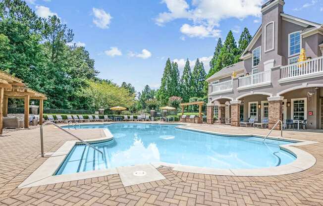 A large outdoor swimming pool surrounded by a brick patio and a house.