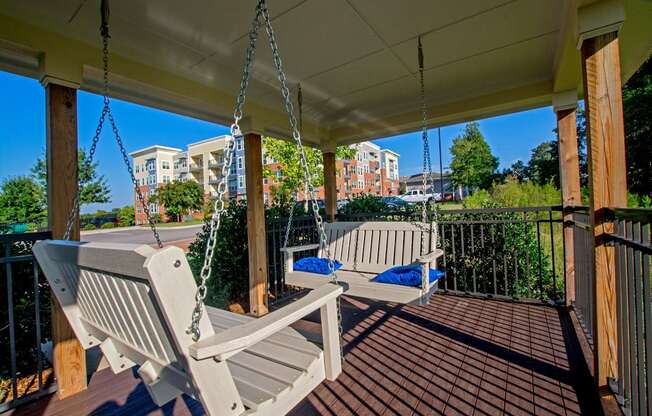 A porch swing hangs from a chain on a wooden porch.