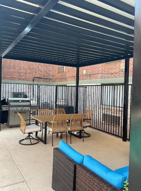 a patio with a table and chairs and a grill
