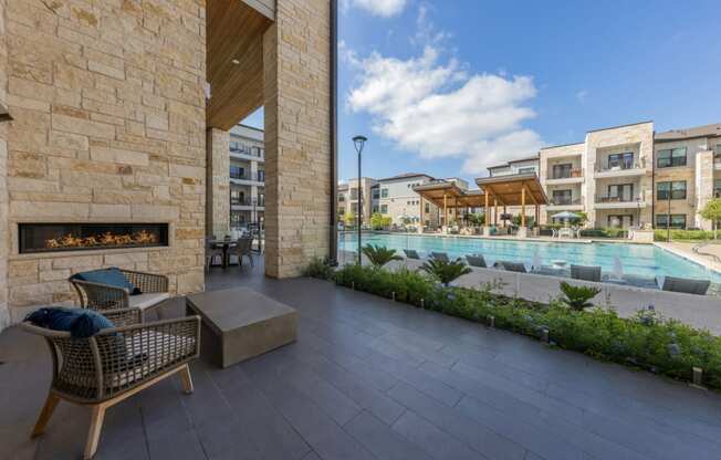 Lenox SoCo Apartments  patio with chairs and a fireplace next to a pool