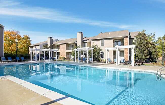 A large swimming pool in front of a building with a white pergola.