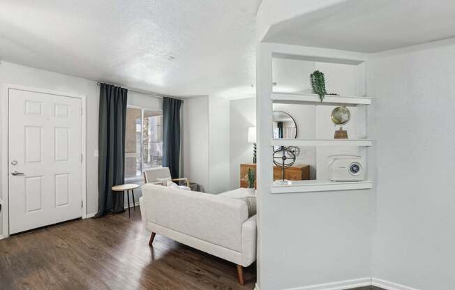 A white couch sits in a room with a white wall and a white door.