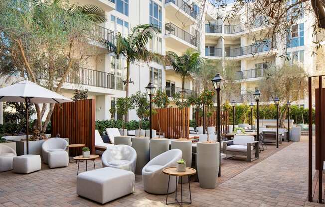 A patio area with white furniture and a building in the background.