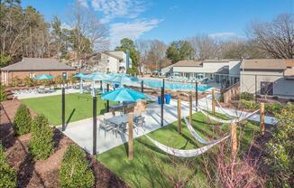 a backyard with hammocks and umbrellas and houses in the background