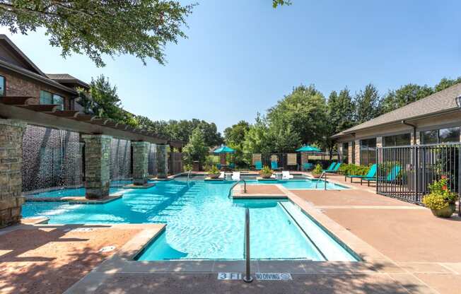 a swimming pool with chairs and umbrellas in front of a house