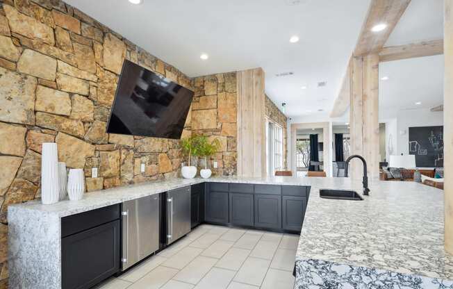 the kitchen has a large island and a stone wall with a tv on it