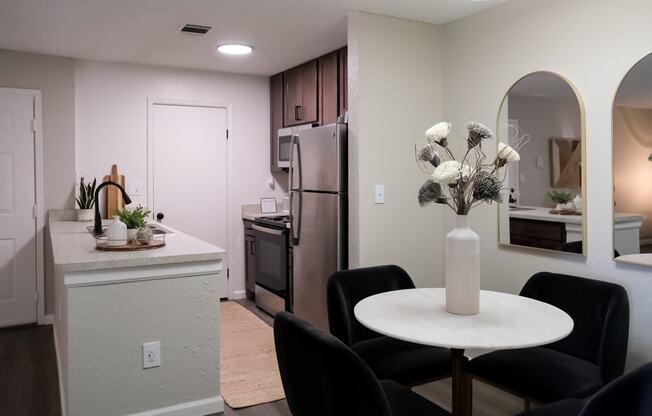 a dining area with a small white table and four black chairs