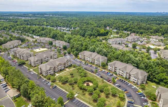 A bird's eye view of a residential area with multiple apartment buildings and a parking lot.
