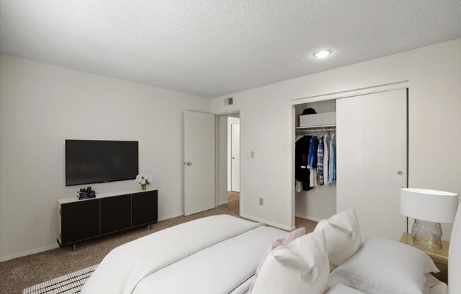 a bedroom with a large white bed and a tv