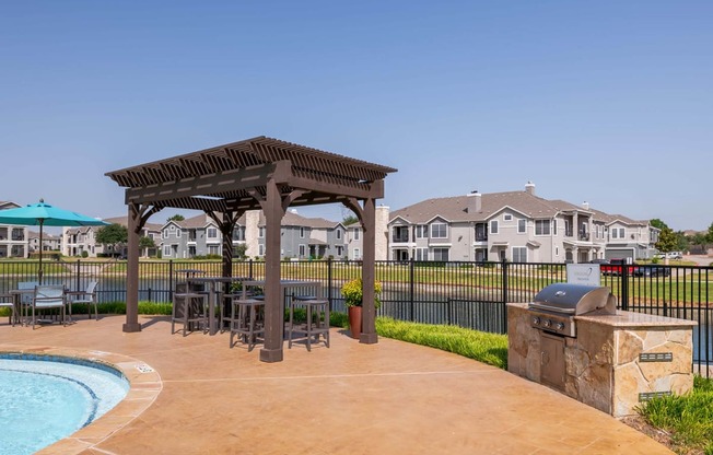 a backyard with a pool and patio with chairs and a grill