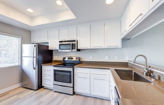 a kitchen with white cabinets and stainless steel appliances