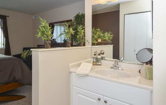 a bathroom with a sink and a mirror and a bedroom with a bed