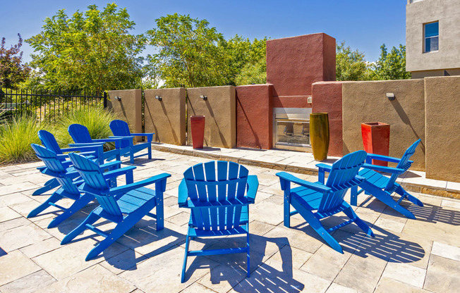 a group of blue chairs on a patio with a fire pit