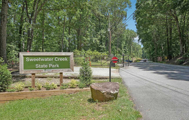A sign for Sweetwater Creek State Park is in front of a wooded area.