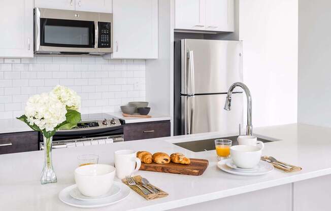 A kitchen with white cabinets and a white countertop with breakfast items on it at The Pennsylvanian Apartments, Pittsburgh, PA, 15222
