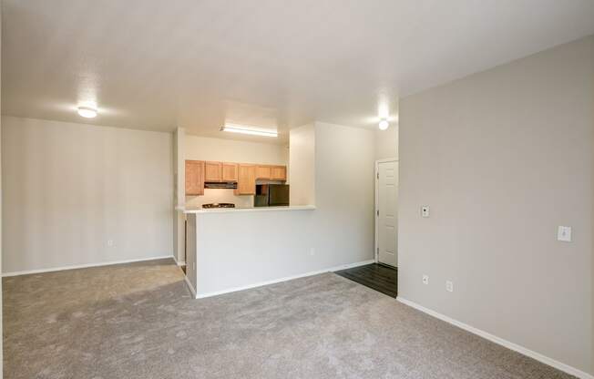 the living room and kitchen of an empty home with white walls and carpet