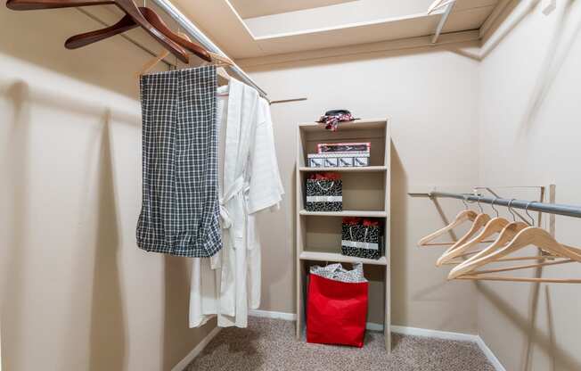a walk in closet with a rack of clothes and a red bag on the floor