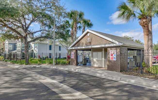 A building with a sign that says "Parking" is surrounded by trees and a fence.