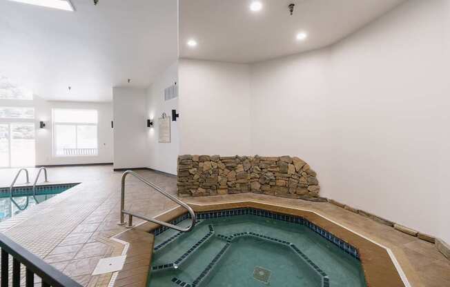 A large indoor swimming pool with a stone wall.