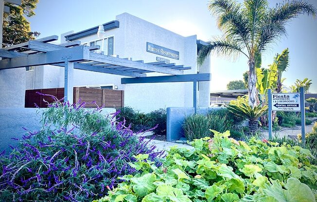 a white building with a blue awning and a palm tree in the background at Fiesta Apts, Lompoc, 93436