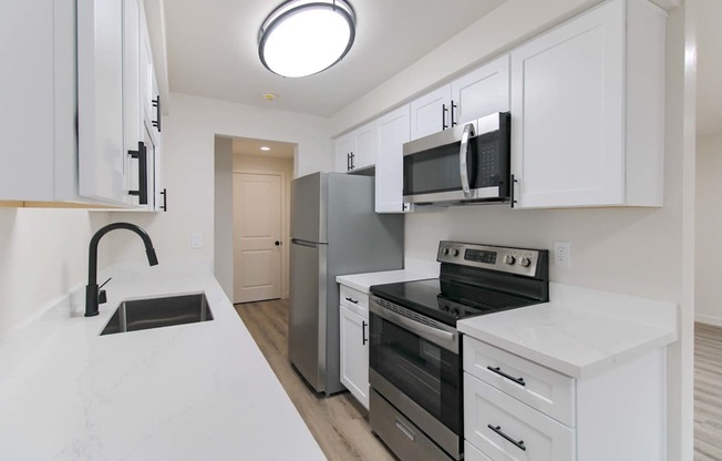 Bright kitchen with white cabinets and plank flooring at Melrose on 91 Redmond