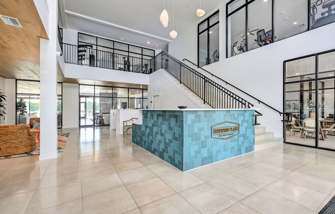 a large lobby with a staircase and a blue tiled reception desk