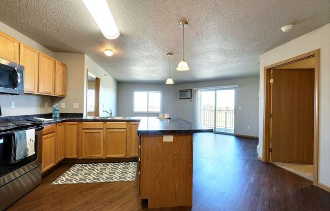 an empty kitchen and living room with wood flooring and a counter top. Fargo, ND East Bridge Apartments