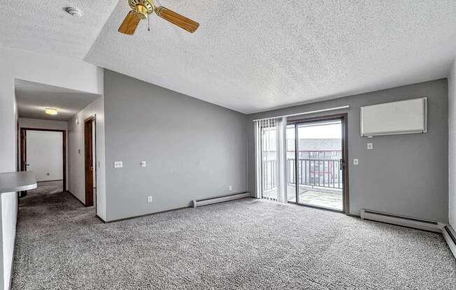 an empty living room with a ceiling fan and a sliding glass door