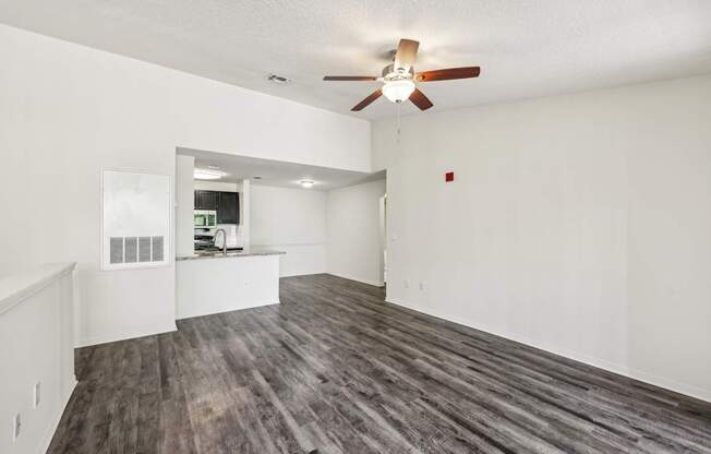 A room with a ceiling fan and wooden flooring.