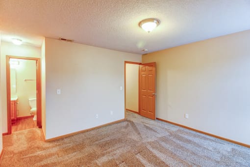 an empty living room with a door to a bathroom