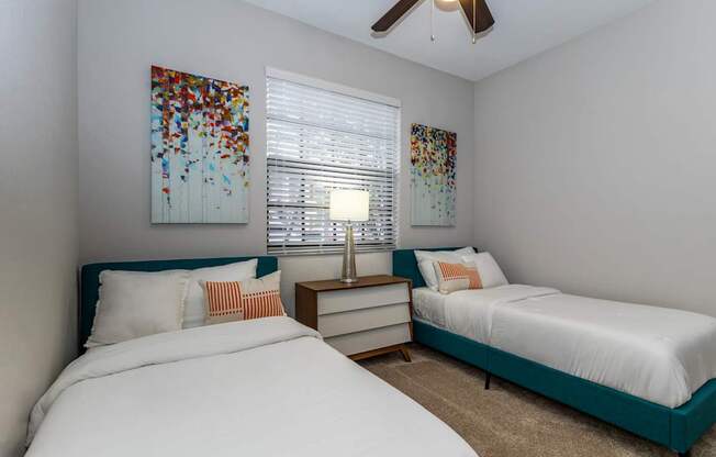 A bedroom with two beds and a ceiling fan.