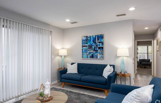 A living room with a blue sofa and a painting on the wall.
