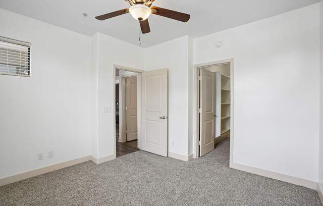 A room with a ceiling fan and two doors.