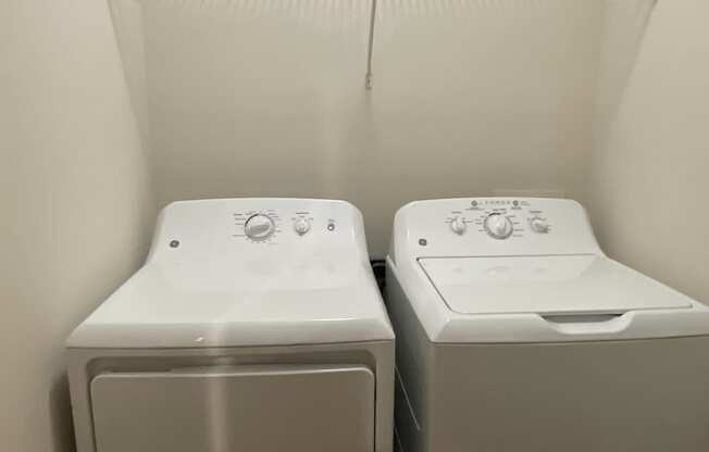 two washers and dryers in a room with a white wall