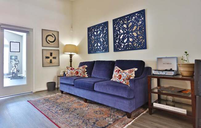 A resident lounge with a sofa, rug, and wall art at The Inverness Apartments in Houston, TX