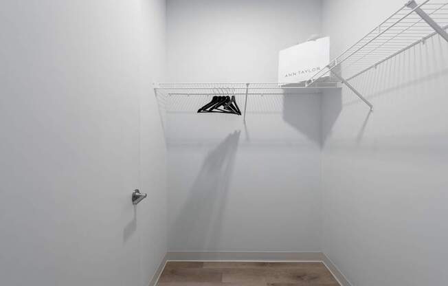 a walk in closet with a white wall and a shoe rack on the wall