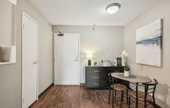 A room with a table and chairs and a painting on the wall.